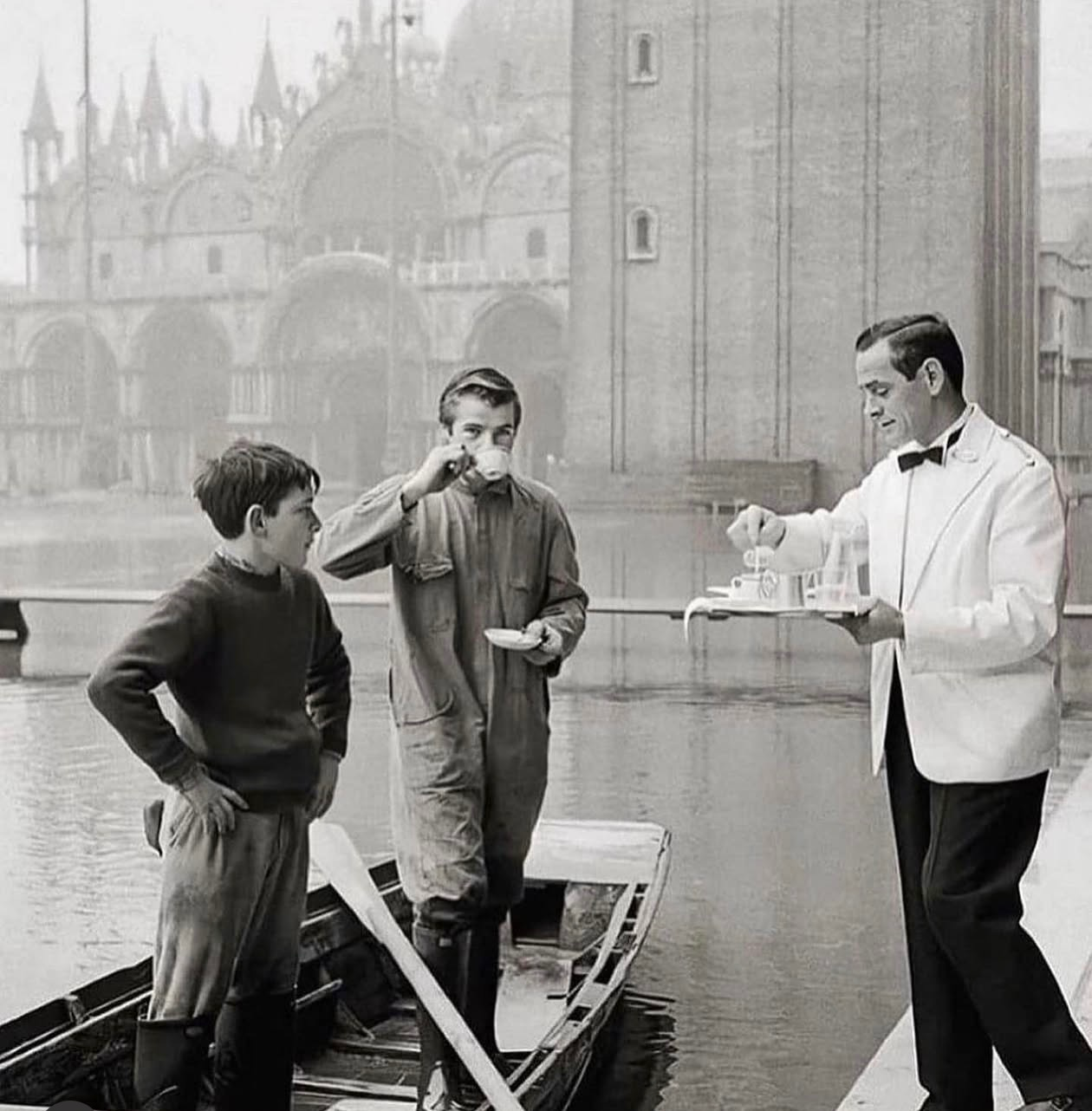 A waiter serving guests from a gondola in Venice — the spirit of hospitality without boundaries